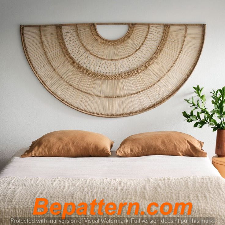 a bed with two pillows and a plant in front of the wall hanging above it