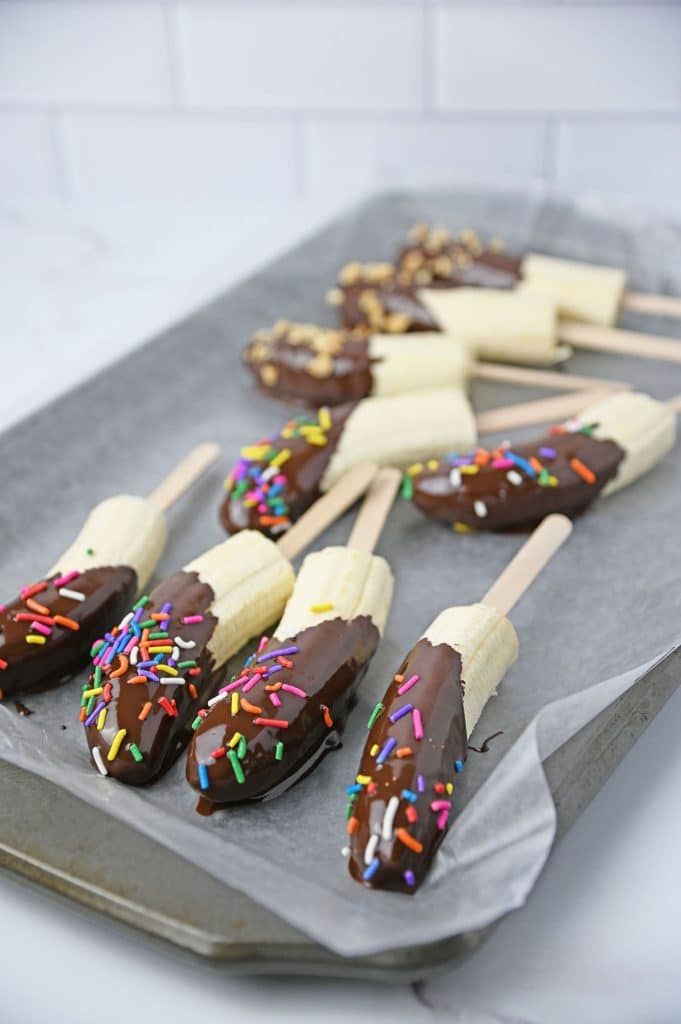 chocolate dipped bananas with sprinkles and marshmallows on a tray