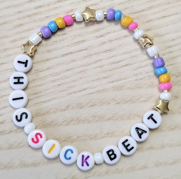 a bracelet with the words sick beat written in different colors and letters on it, sitting on a wooden surface