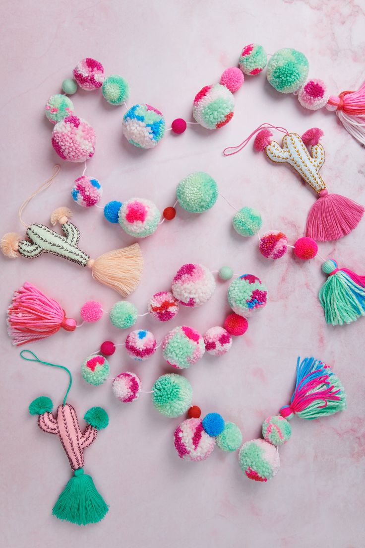 various pom poms and tassels laid out on a pink surface