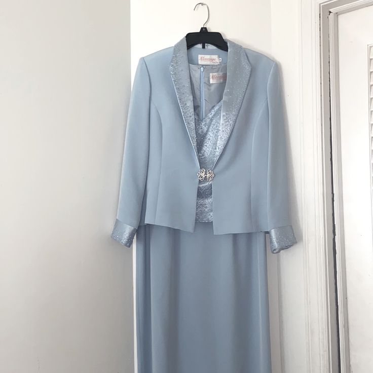 a woman's blue dress and jacket hanging on a white wall next to a door