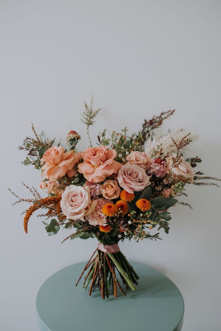 a bouquet of flowers sitting on top of a blue table next to a white wall