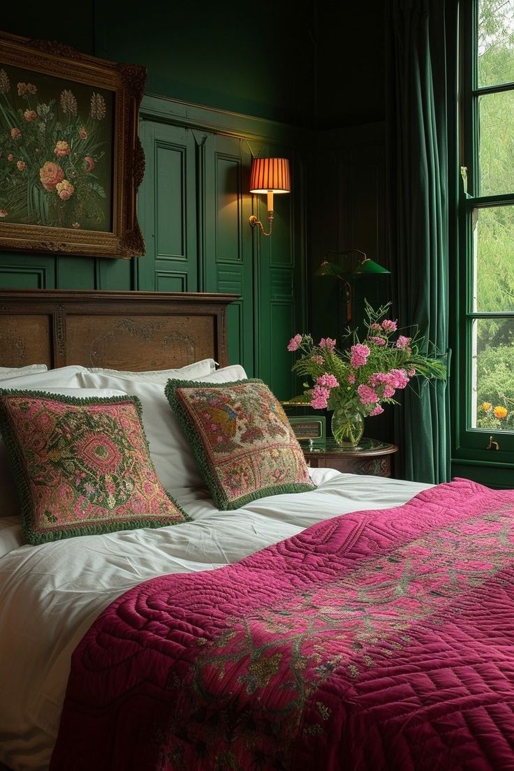 a bed with pink and green comforters in a bedroom next to a large window