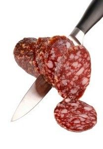 two slices of salami on a white background with a knife in the foreground