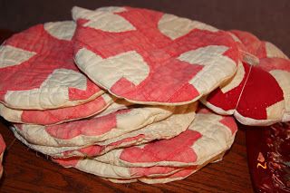 a pile of pink and white cloths sitting on top of a wooden table next to a red vase