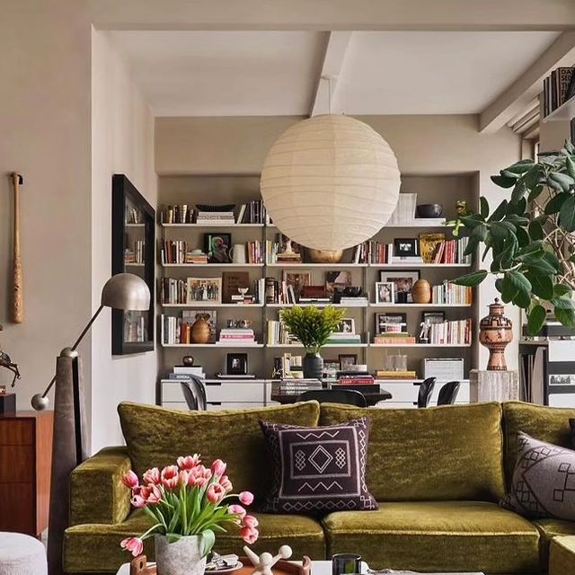 a living room filled with furniture and bookshelves next to a plant in a vase