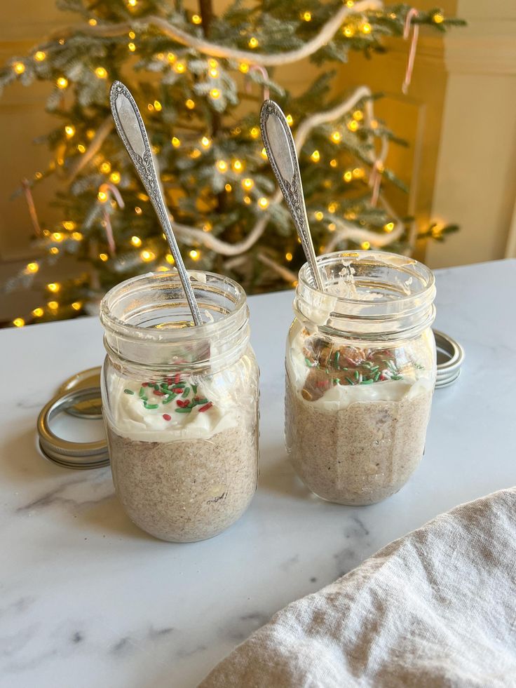 two jars filled with food sitting on top of a table next to a christmas tree