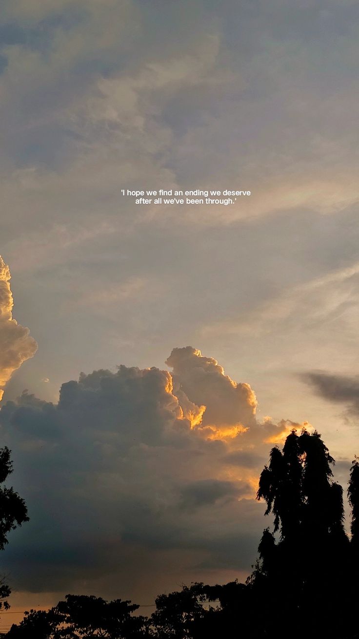 the sky is filled with clouds as the sun sets in the distance behind it and there are trees below