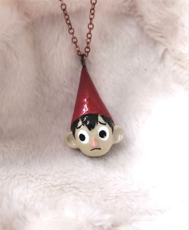 a necklace with a little boy wearing a red hat on it's head and eyes