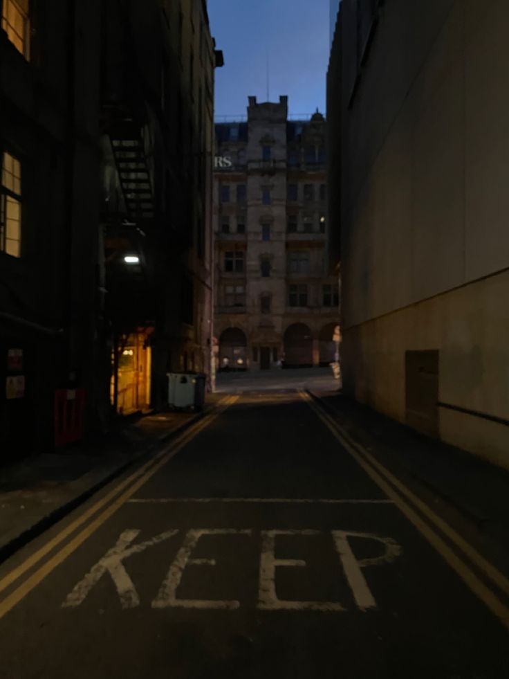 an empty street with the word keep painted on it in white chalk next to tall buildings