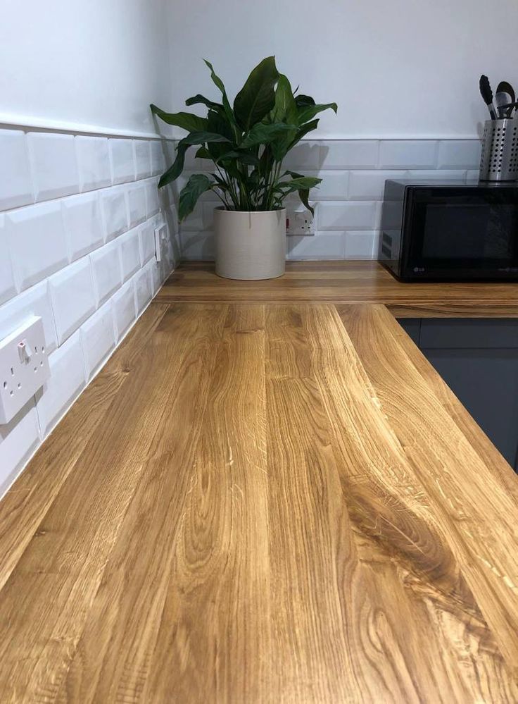 a wooden counter top in a kitchen next to a microwave and potted green plant