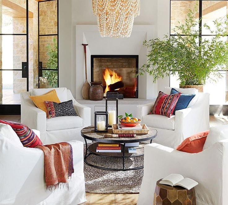 a living room filled with white furniture and a fire place in the middle of it