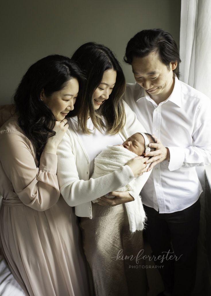 three people standing next to each other holding a baby