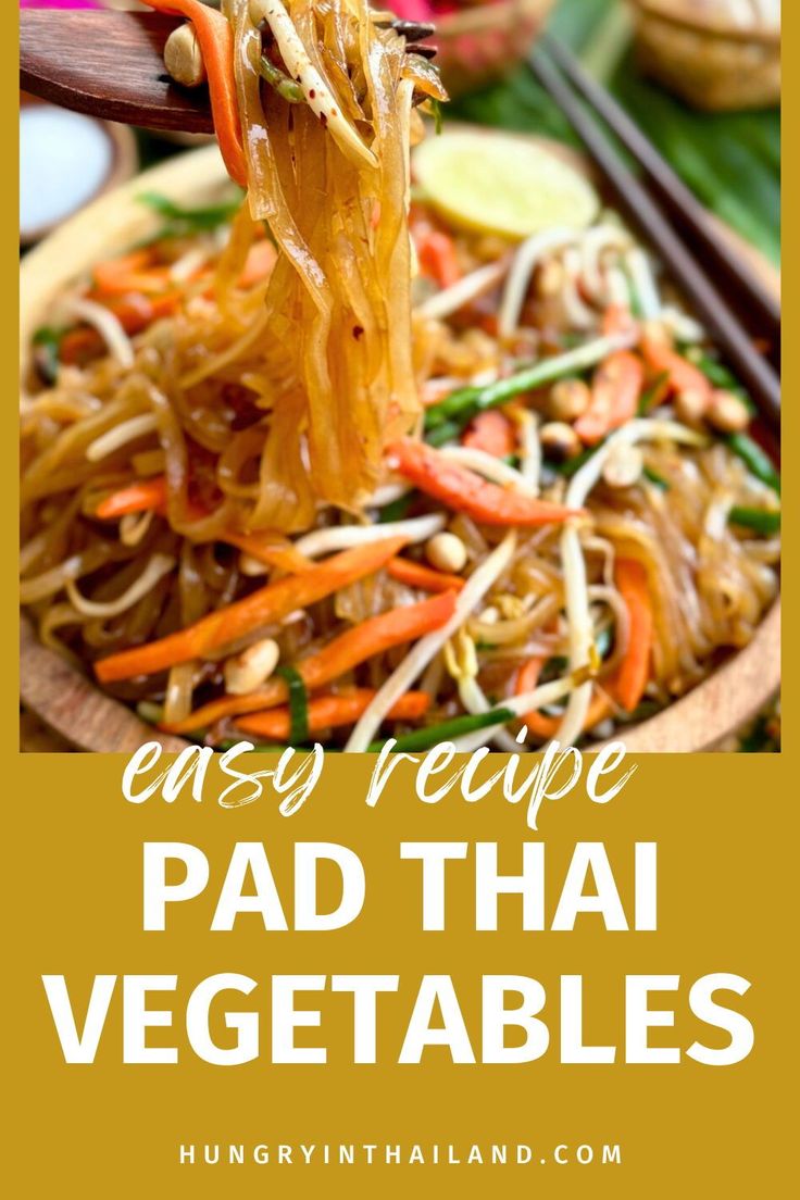 pad thai noodles with carrots and vegetables being lifted from a wooden bowl by chopsticks