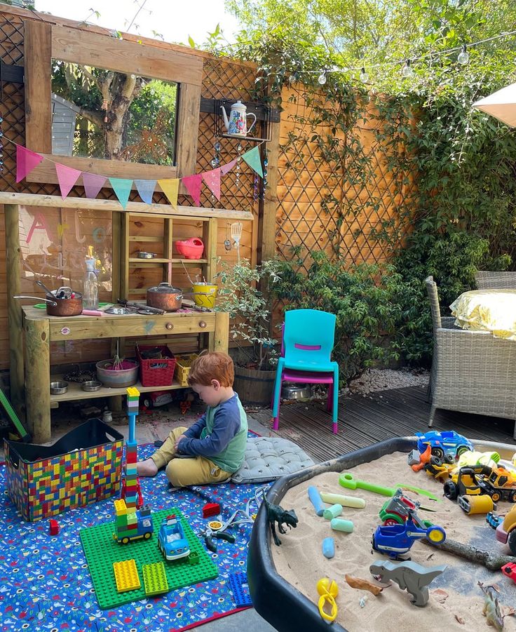 a little boy playing in his backyard with toys and building blocks on the rugs