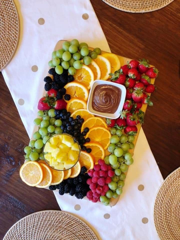 a platter filled with fruit on top of a table next to wicker place mats