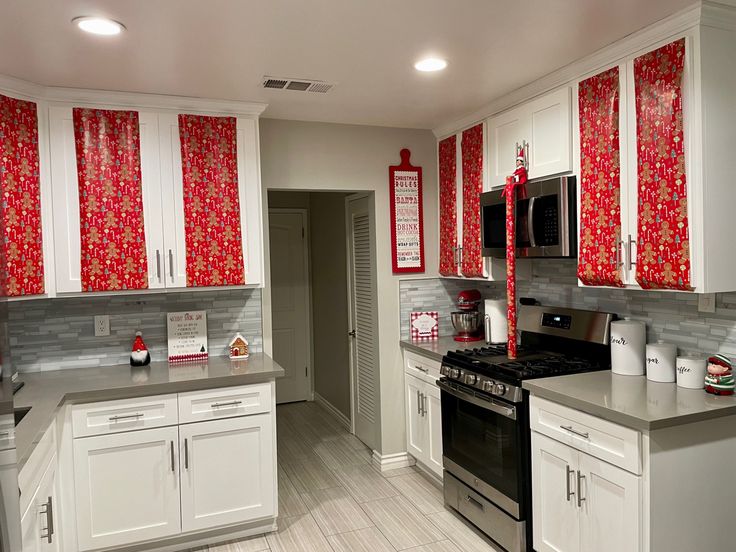 a kitchen with white cabinets and red curtains