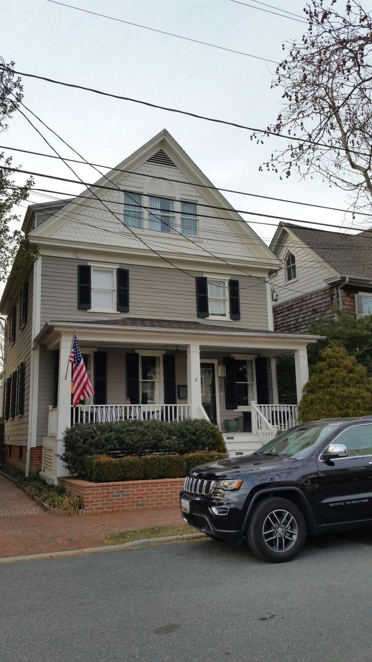 a black jeep parked in front of a white house with an american flag on it