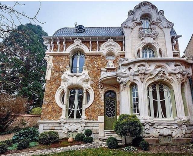 an elaborately designed house sits in the middle of a grassy area with trees and bushes