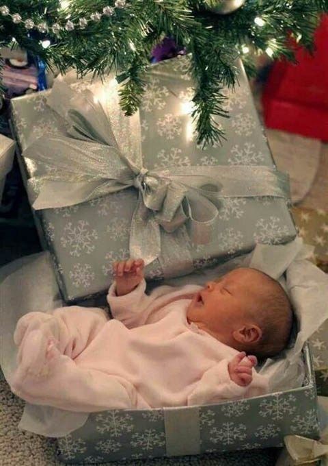 a baby is laying in a box under a christmas tree