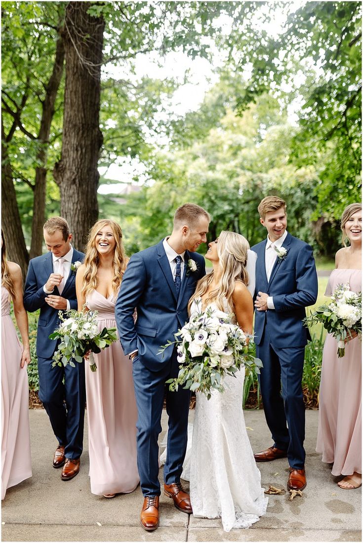 a group of people standing next to each other in front of trees and flowers on the ground