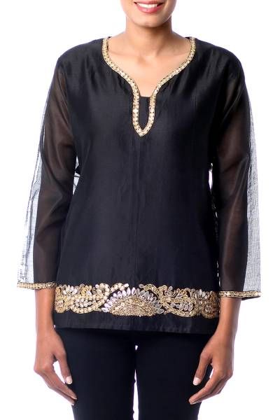 A shimmering black cotton and silk blend becomes a beautiful blouse by Isha Jain. Intricate gota embroidery combines with beads and sequins to surround the sleeves and neckline while a wide band trims the front hem. Similar to applique gota embroidery involves adding a different fabric to the background to create new textures. Embellished Festive Blouse For Eid, Elegant Sequin Blouse For Eid, Eid Festive Embellished Blouse, Designer Black Sequined Blouse, Embellished Long Sleeve Blouse For Eid, Embellished Long Sleeve Chanderi Kurta, Embellished Bollywood Blouse For Eid, Embellished Blouse For Eid Party, Bollywood Sequined Blouse For Eid