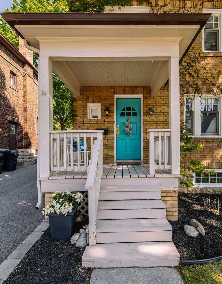 the front porch of a house with steps leading up to it and a blue door