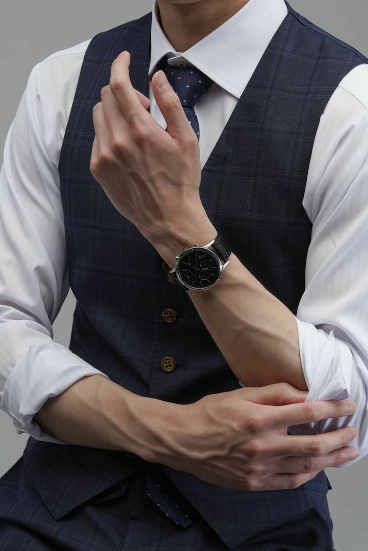 a man wearing a suit and tie holding his hands together