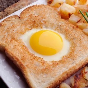 an egg in a toast with potatoes on the side