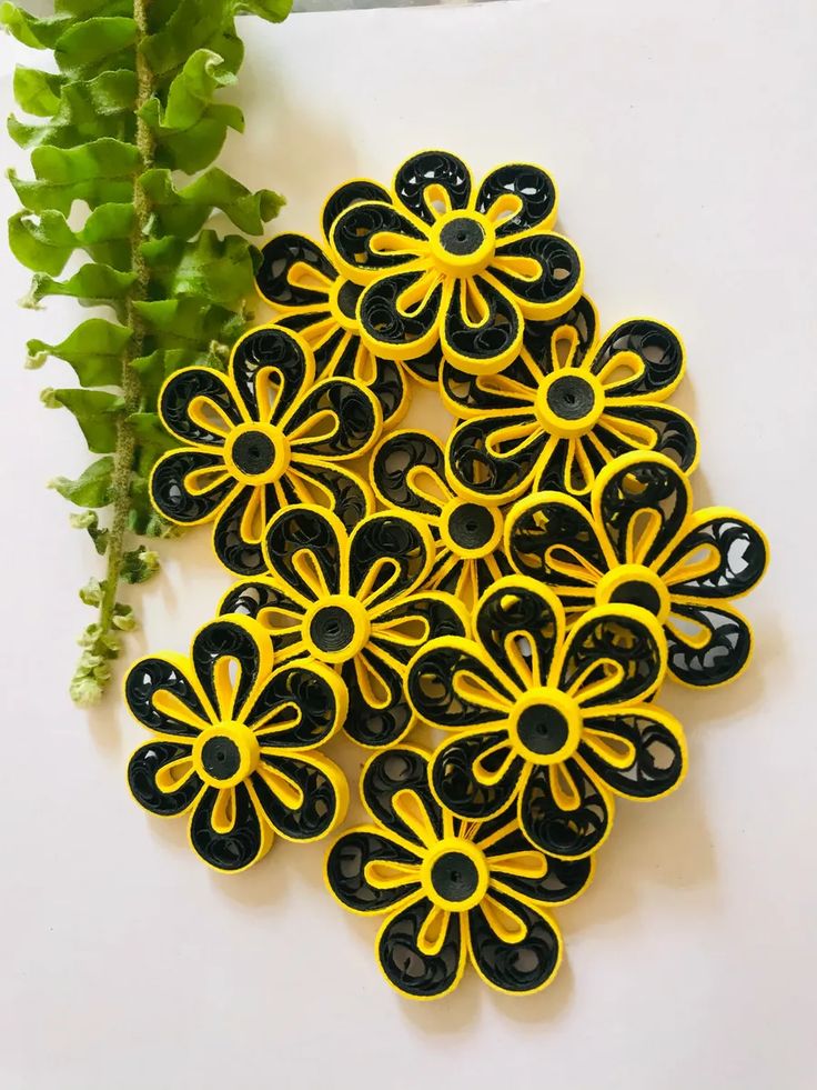 yellow and black flower broochies sitting on top of a white surface next to a green plant