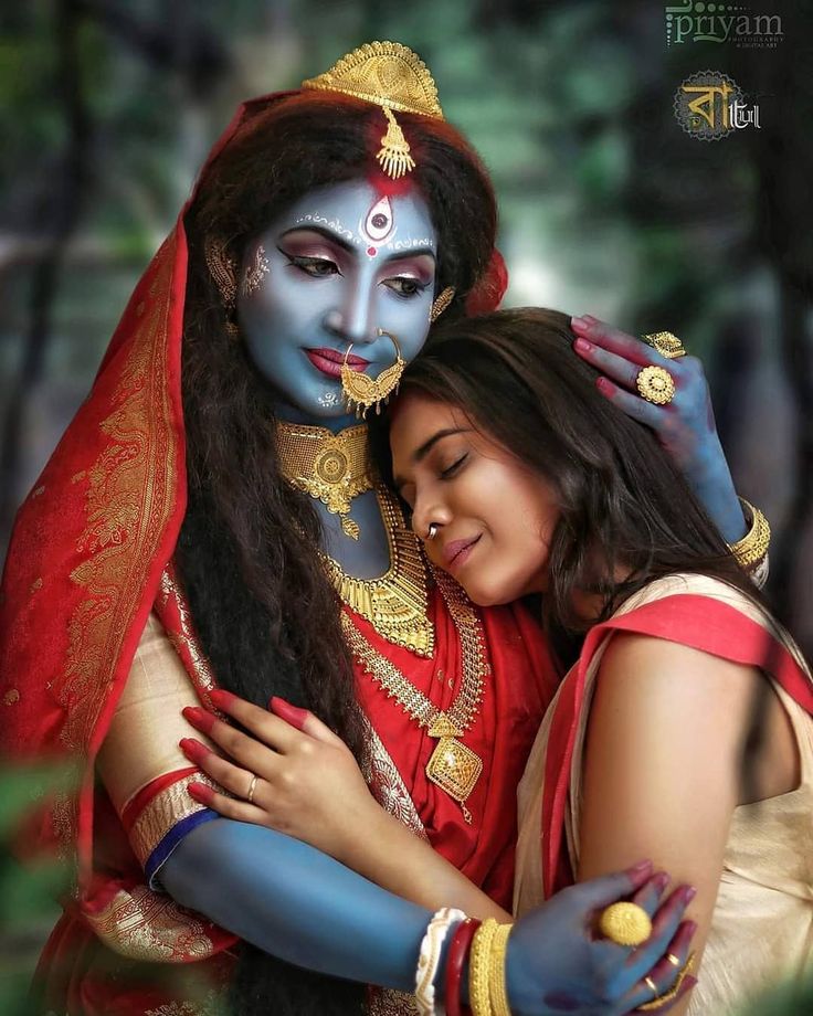 two people are hugging each other in front of some trees and bushes, one is dressed as the hindu god