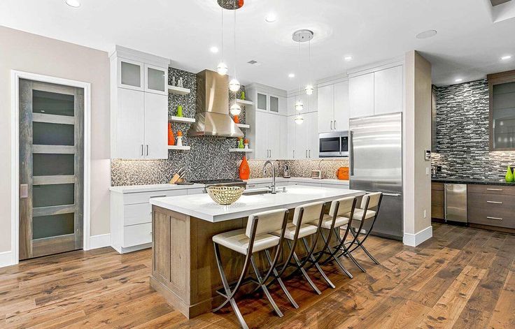 a large kitchen with white cabinets and wooden flooring, along with stainless steel appliances