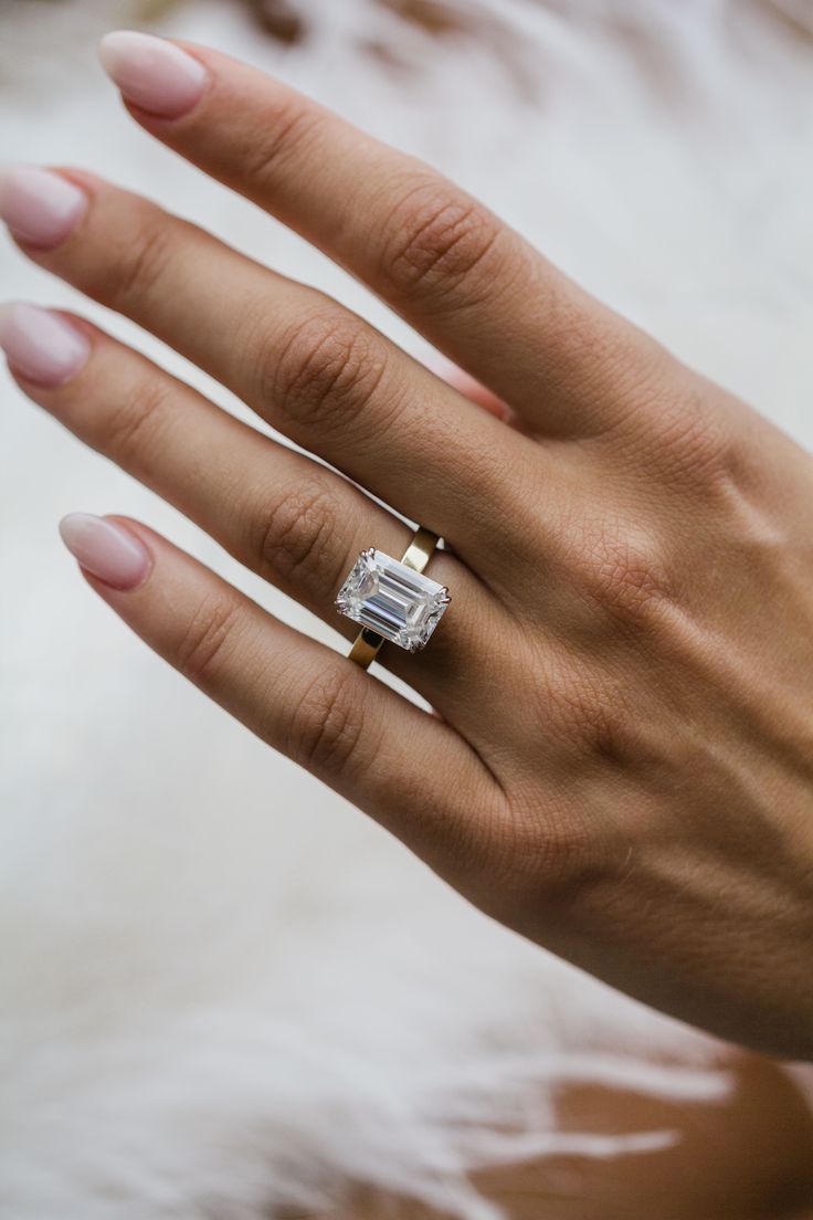 a woman's hand with a diamond ring on her left hand and white fur in the background