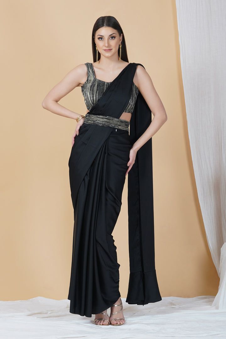 Ooze style and class in this ready to wear saree in a stunning black hue. With a contrasting blouse and belt, this saree is a classic pick for cocktail parties, soirées and weddings!Style Ready to Wear Saree Embellished Belt Contrasting Blouse Classic Black hue Armani silk fabric Specifications Model height - 5'9" Model wearing - S Elegant Party Pre-draped Saree With Zari Work, Festive Black Pre-draped Saree With Self Design, Festive Evening Pre-draped Saree With Cutdana, Elegant Black Pre-draped Saree With Zari Work, Party Wear Saree Set For Evenings, Formal Floor-length Pre-draped Saree For Diwali, Formal Fitted Pre-draped Saree With Cutdana, Elegant Pre-draped Saree For Diwali Evening, Evening Pre-draped Saree For Diwali With Unstitched Blouse