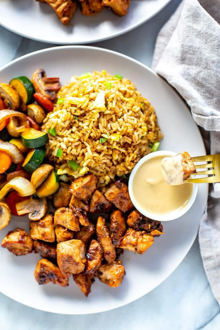 a white plate topped with chicken, rice and veggies