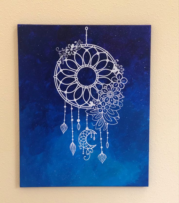 a painting on a wall with a blue background and white dream catcher hanging from it's side