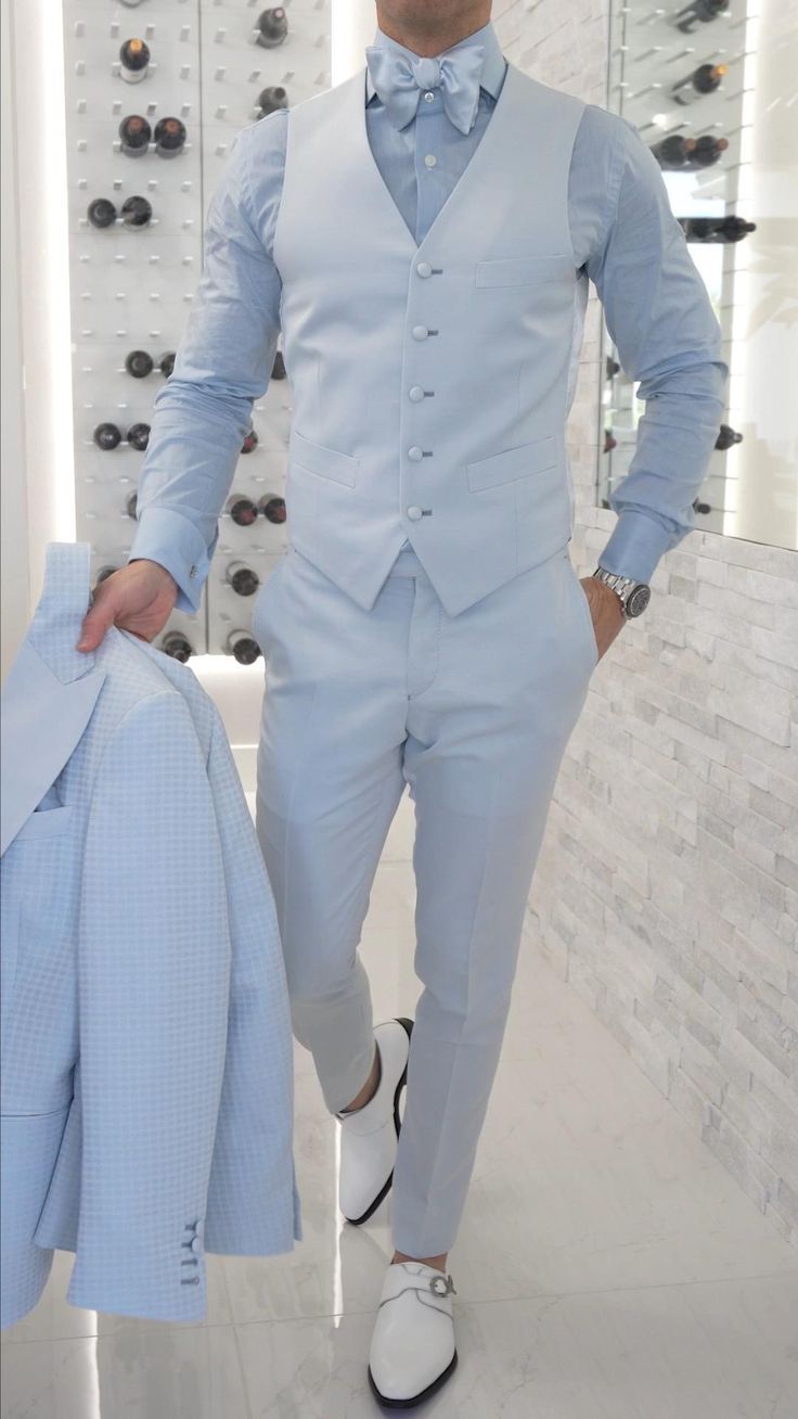 a man in a blue suit and white shoes is standing next to a jacket rack