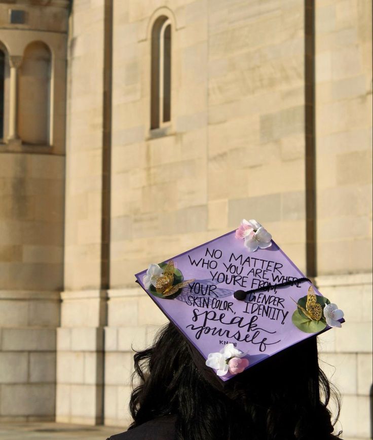 a woman wearing a purple graduation cap with writing on it's side in front of a stone building