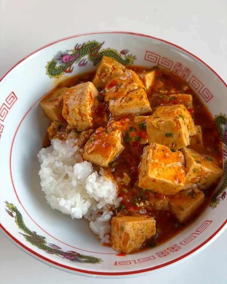 a bowl filled with tofu and rice on top of a table