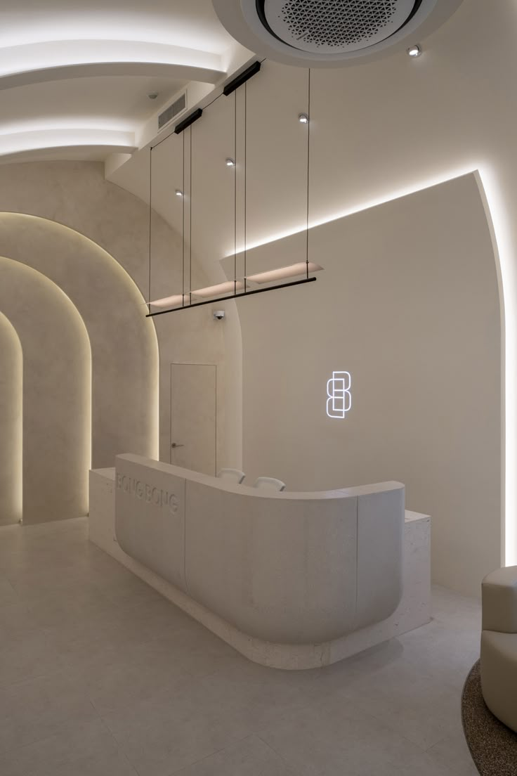 a white reception area with circular lights and curved ceiling lighting above the counter, along with round stools