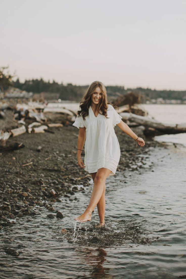 a woman is walking in the water at the beach