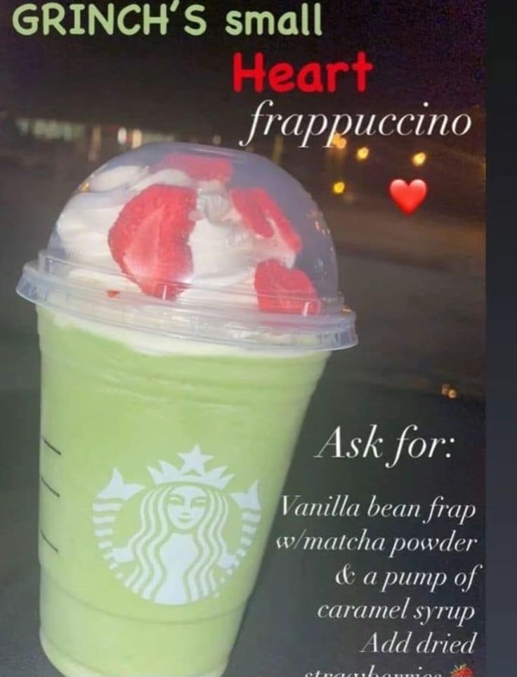 a green drink with whipped cream and strawberries in it is on the table next to a sign that says, grin's small heart frappuccino