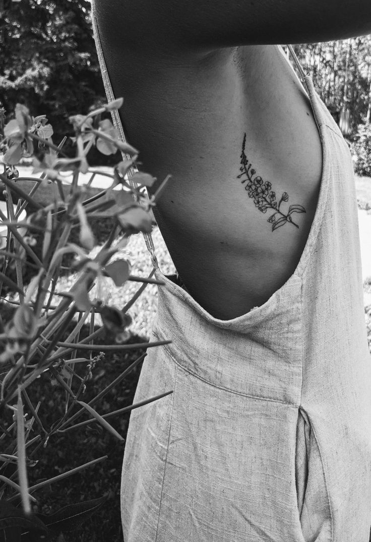 black and white photo of a woman's back with a flower tattoo on her left side