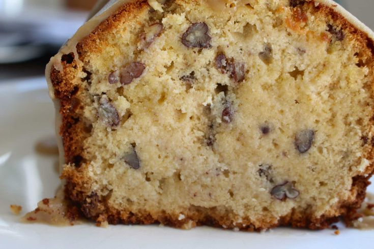 a close up of a piece of cake on a plate with icing and chocolate chips