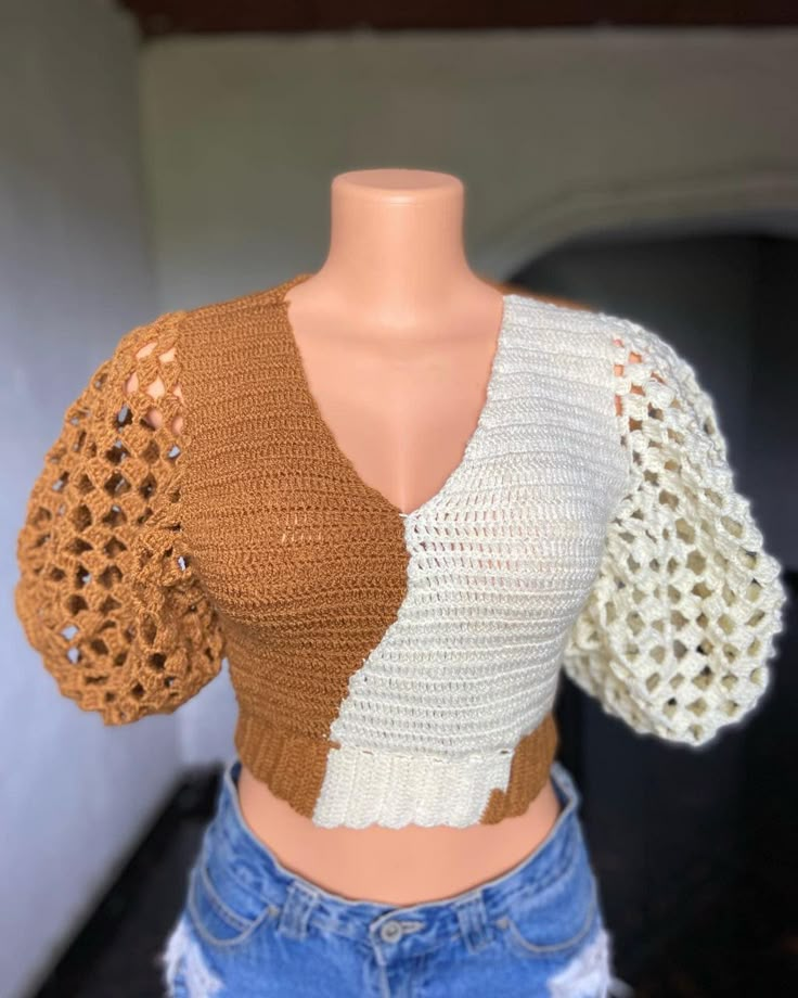 a female mannequin wearing a brown and white top with crocheted sleeves