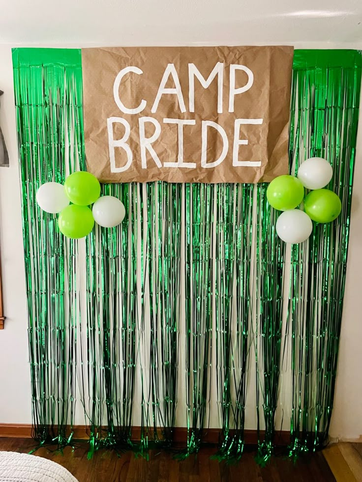 a green and white party decoration with streamers, balloons and a sign that says camp bride