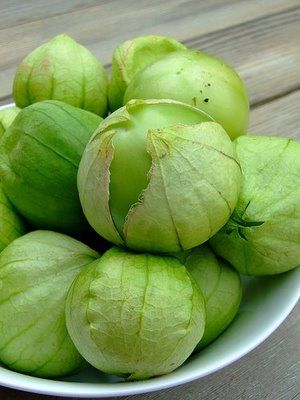 a white bowl filled with green fruit on top of a wooden table