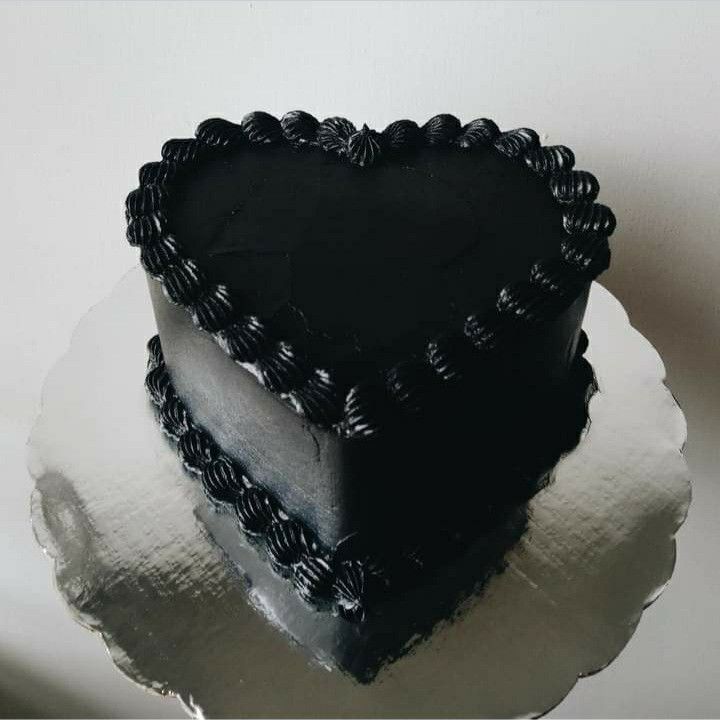 a heart shaped black cake sitting on top of a white plate