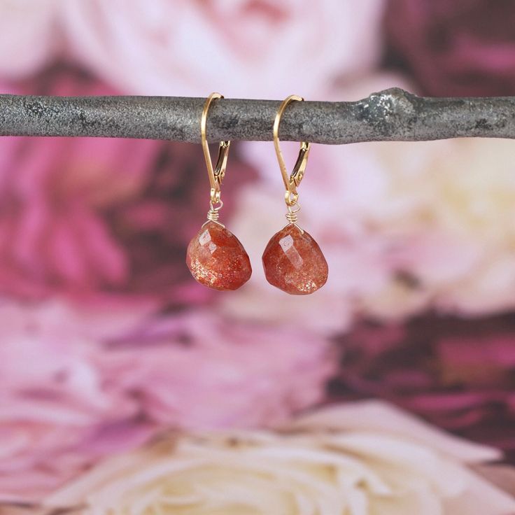 Electric Sunstone gems full of sparkly facets hang from secure, hinged-back ear wires (the back of the ear wire clicks into place, making the earrings impossible to lose when you're wearing them). You can choose from 14k gold fill or sterling silver for your earrings. The total length of the earrings is just over 1 inch from the curve of the ear wire to the bottom of the drop. The Sunstone gems are plump teardrops measuring 10 millimeters long and 11 millimeters wide, and the color is a deep, rich copper orange with iridescent shimmer. These are lightweight earrings that will get you lots of compliments on the color and sparkle. Gold Faceted Crystal Earrings For Anniversary, Gold Faceted Crystal Earrings For Gift, Amber Teardrop Birthstone Jewelry, Gold Crystal Gemstone Earrings For Anniversary, Rose Gold Dangle Jewelry With Lever Back Ear Wires, 14k Gold Faceted Drop Earrings, Faceted Teardrop Dangle Earrings For Gift, Faceted Teardrop Dangle Earrings As Gift, Faceted Drop Earrings As Gift