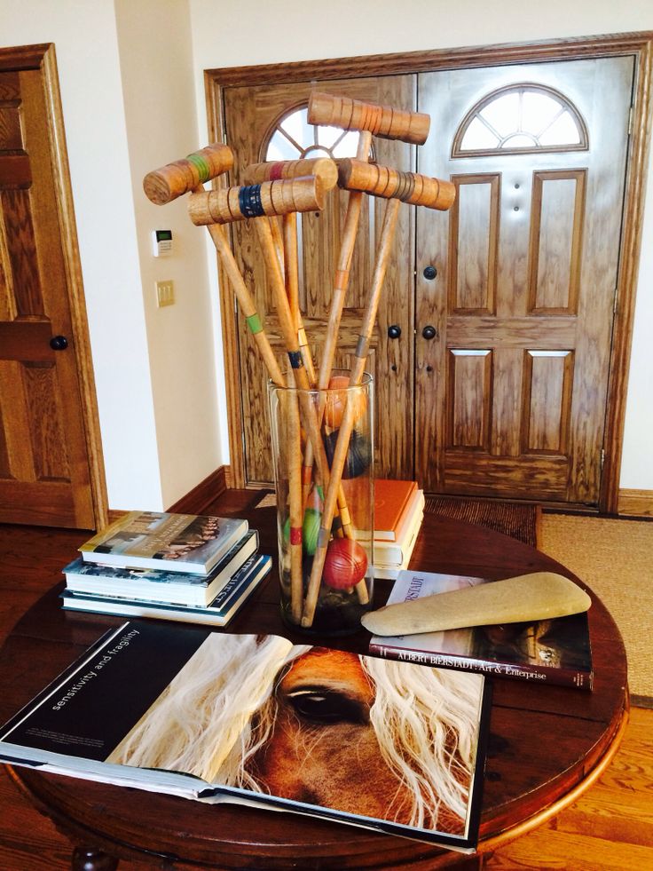 a wooden table topped with books and a vase filled with bamboo stick art work on top of it